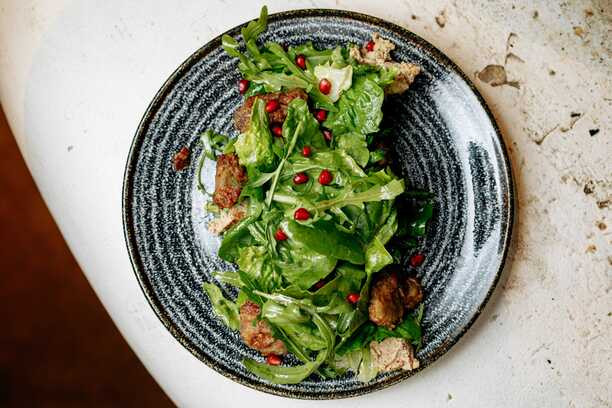 Salat Tbilisuri z kuryachoyi pechinky Salat na osnovi khrustkoho miksu salatnoho lysta, rukoly z kulʹkamy z horikhovoyi pasty ta teployu nizhnoyu kuryachoyu pechinkoyu, flambovanoyu v konʹyaku z dodavannyam chasnyku ta vynnoho sousu. Podayetʹsya z nevelykoyu kilʹkistyu sousu tkemali ta zernamy hranatu. Tbilisuri salad from chicken liver